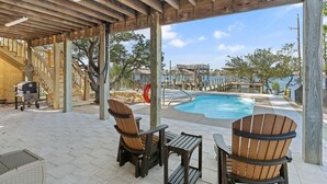 A wooden deck with a pool, outdoor seating, and a view of a building in the background. - Cotton Bayou Fish Camp (Orange Beach)