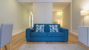 Un salon moderne avec un canapé bleu, un meuble blanc et un tapis gris.