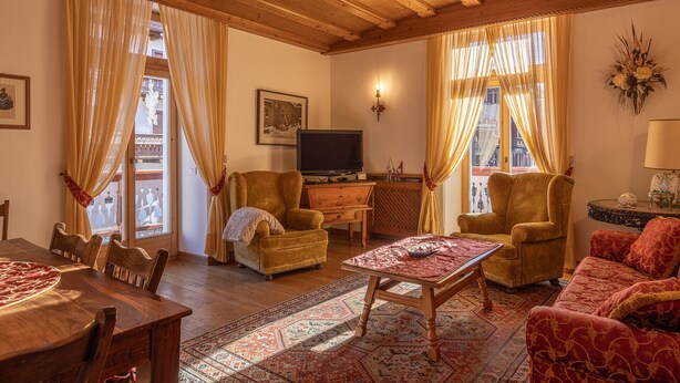 A cozy living room with wooden beams, a TV, two armchairs, a sofa, and a dining table. - Casa Ciclamino, in the center of Cortina d'Ampezzo (Cortina d´Ampezzo)