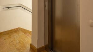 A hallway with a marble floor, a metal handrail, and a closed elevator door. - Casa Ciclamino, in the center of Cortina d'Ampezzo (Cortina d´Ampezzo)