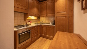 A kitchen with wooden cabinets, a stove, and a sink. - Casa Ciclamino, in the center of Cortina d'Ampezzo (Cortina d´Ampezzo)