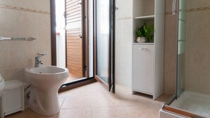 Une salle de bain équipée d’un bidet, d’un lavabo, d’un meuble de rangement et d’un espace douche.
