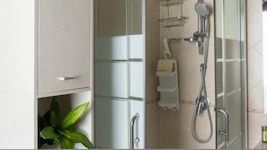 A bathroom with a glass shower enclosure, a white cabinet, a plant, and a towel rack. - La Casa di Asia in Tanaunella (Budoni)