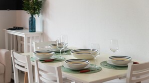A dining table set with white chairs, bowls, and wine glasses. - La Casa di Asia in Tanaunella (Budoni)