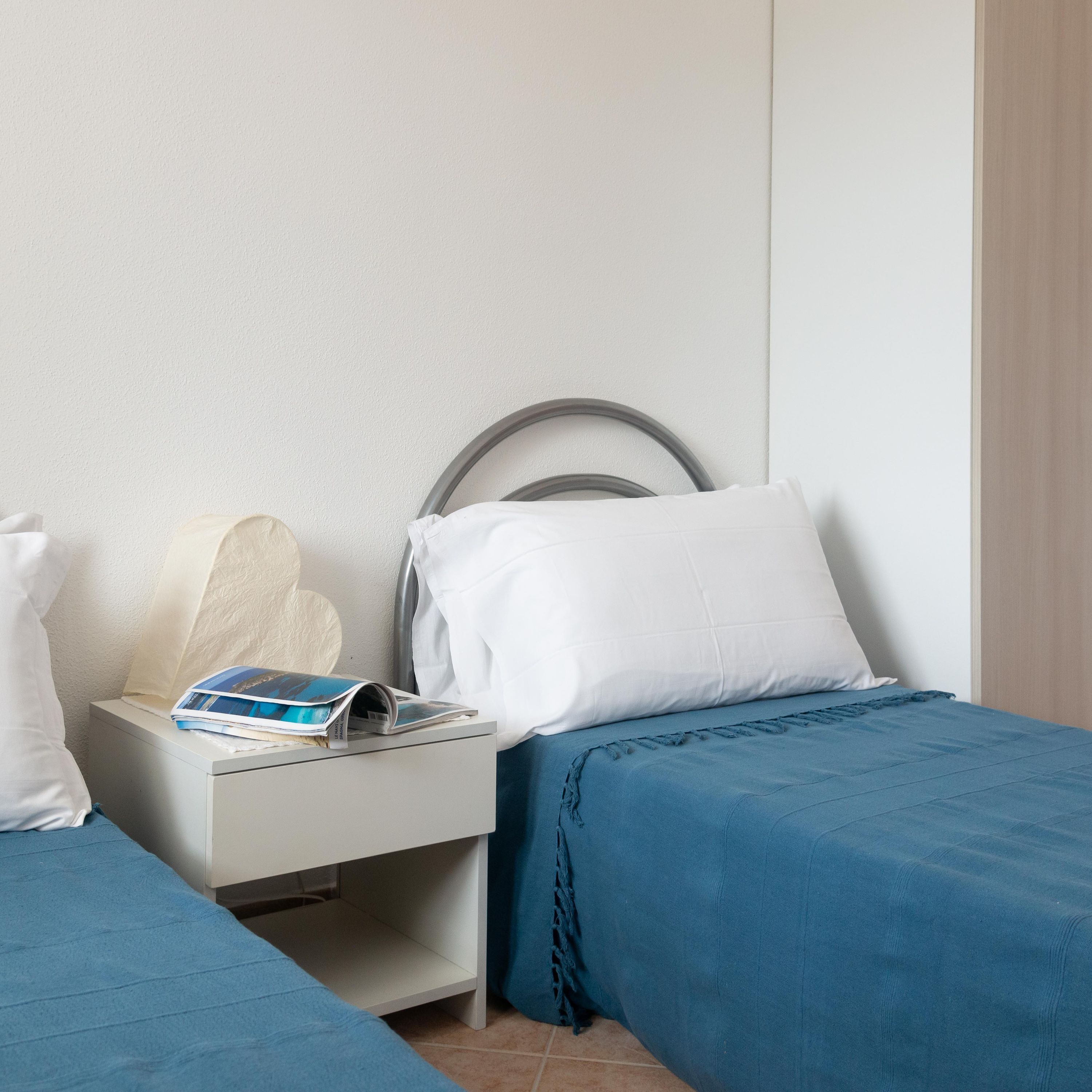 A bedroom with a bed, a nightstand, and a wall-mounted shelf.