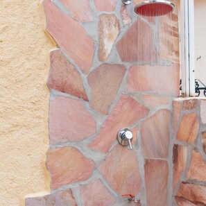 Pared de piedra con ducha y grifo.