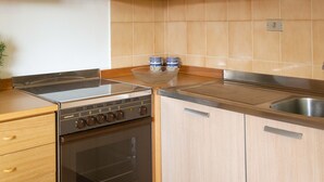 A kitchen with wooden cabinets, a stove, oven, and a sink. - Casa Ficus in Porto Ottiolu (Budoni)