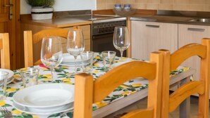 A kitchen with wooden cabinets, a dining table set with plates and glasses, and a potted plant on the counter. - Casa Ficus in Porto Ottiolu (Budoni)