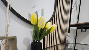 Un intérieur moderne agrémenté d’un miroir rond, d’un banc jaune rembourré et d’une plante en pot aux fleurs jaunes.