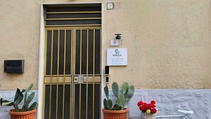 L’entrée d’un immeuble est marquée par une double porte, une enseigne indiquant « Chambre d’hôtes écologique » et un vélo garé à l’extérieur.