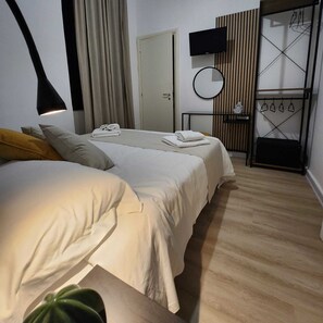 A hotel room with a bed, a bedside table, a TV, a mirror, and a wooden panel wall. - B&B Green (Reggio Calabria)