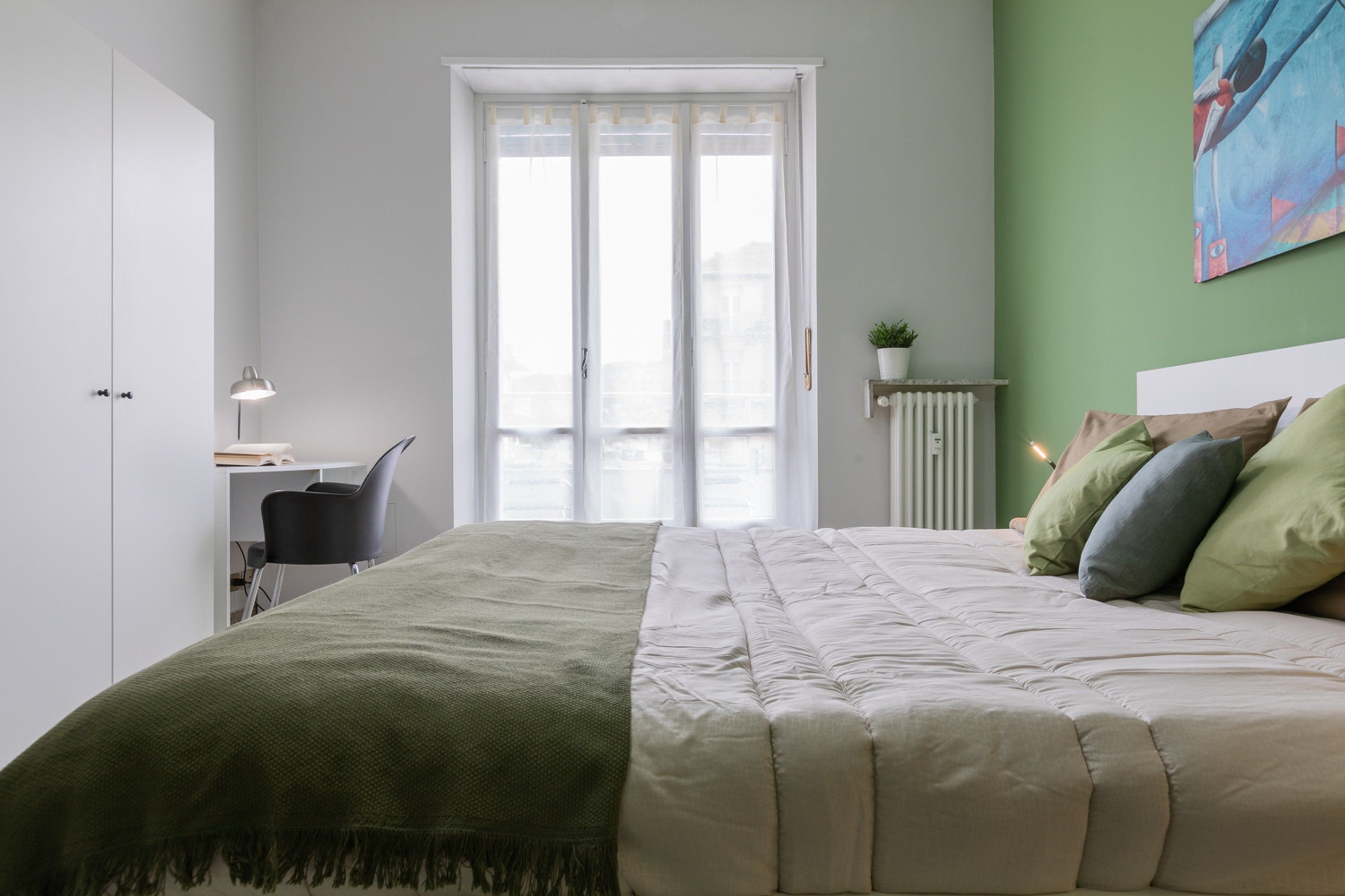 Une chambre à coucher avec un lit, un bureau, une chaise et un radiateur.