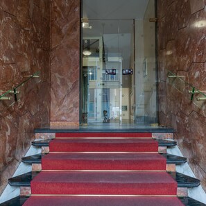 A set of marble stairs leading to a glass door entrance.