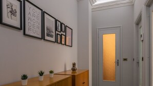 En hall med ett träskåp, krukväxter och inramade tavlor på väggen.