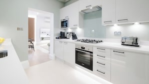 Une cuisine moderne avec des meubles blancs, un four Bosch, un four à micro-ondes et un grille-pain.