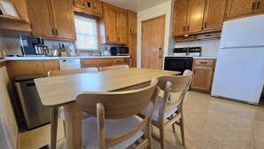 Una cocina con armarios de madera, una mesa de comedor, sillas, un refrigerador y un lavavajillas.