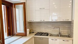 A modern kitchen with white cabinets, a gas stove, and a stainless steel sink. - Modern and Cozy Home at 200 Meters to the Beach (Minori)