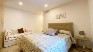 A bedroom with a large bed, a smaller sofa, and a bedside table with a lamp. - Modern and Cozy Home at 200 Meters to the Beach (Minori)