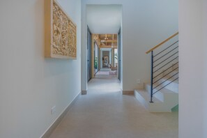 Un pasillo con una escalera, techo de madera y un gran relieve en la pared.