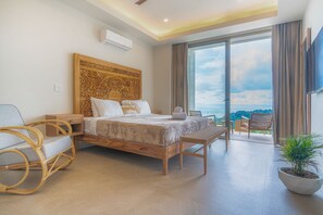 Ein modernes Schlafzimmer mit einem großen Bett, einem hölzernen Kopfteil, einem Nachttisch, einem Sessel, einer Bank und einer Topfpflanze.