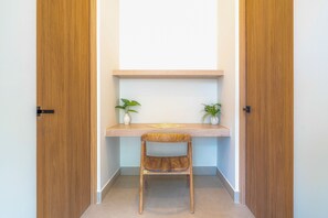 Une pièce d’angle avec un bureau en bois, deux plantes en pot et une chaise.
