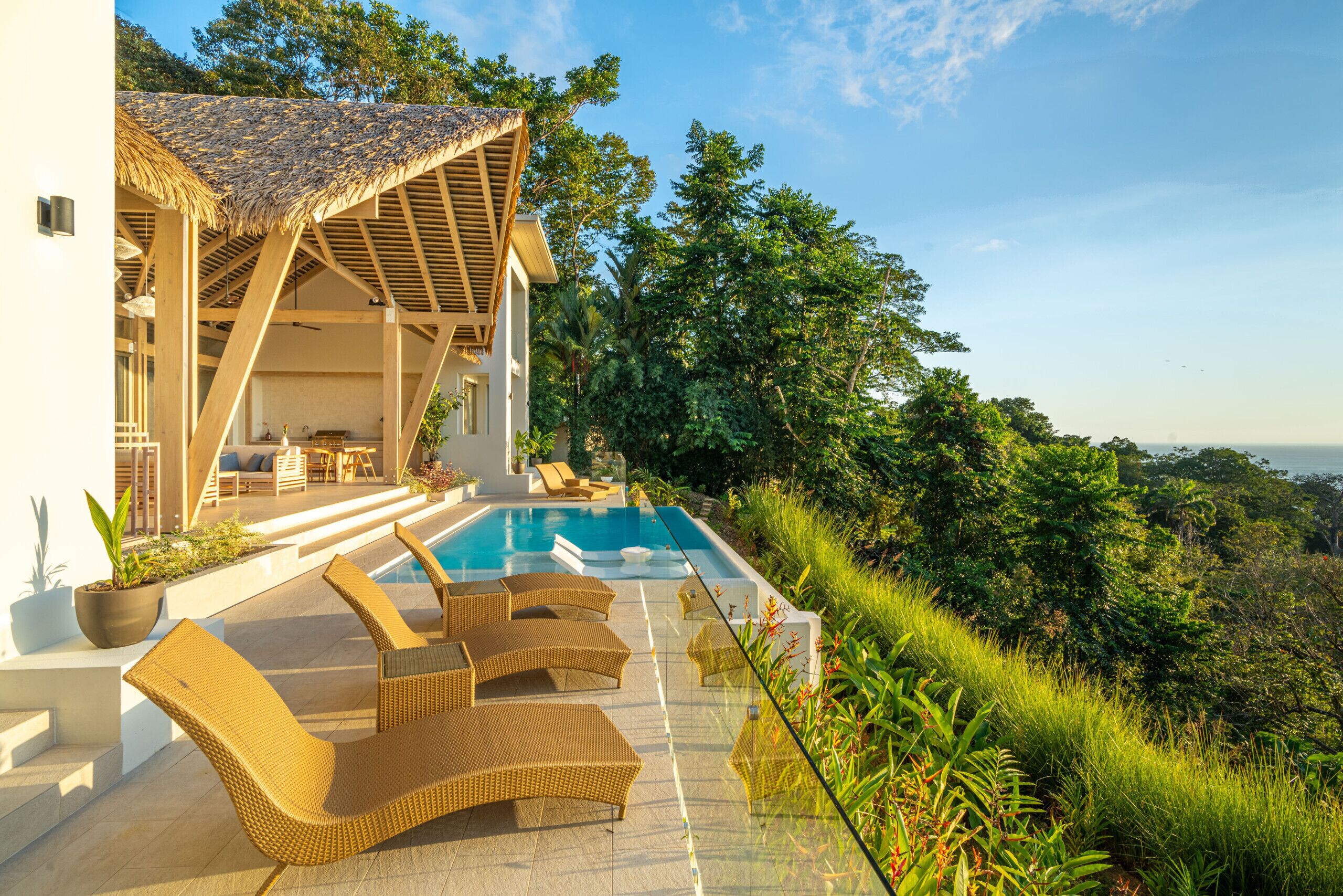 Eine moderne Villa mit Pool, Sitzgelegenheiten im Freien und üppiger Bepflanzung.