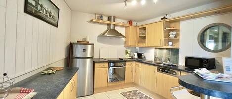 Una cocina moderna con electrodomésticos de acero inoxidable, armarios de madera y un ventanal redondo.