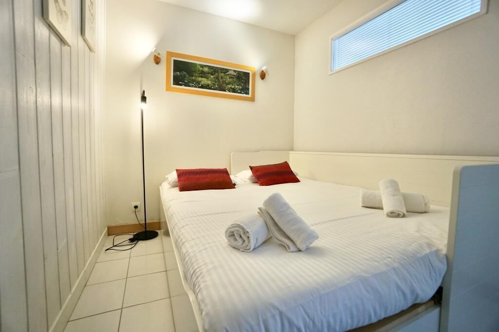 Ein Hotelzimmer mit einem Bett, einer stehenden Stehlampe, einem gerahmten Bild an der Wand und einem Fenster.