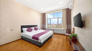 A bedroom with a bed, a window with a view, a flat-screen TV, and a plant. - Binpeng Tianxia Hotel (Harbin)