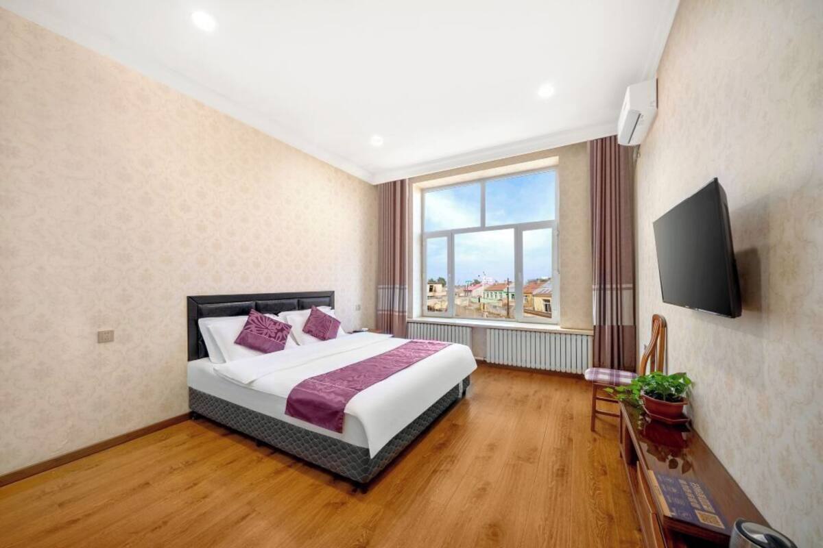 Ein Schlafzimmer mit Bett, Fenster mit Blick, einem Flachbildfernseher und einer Pflanze.