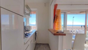 A narrow kitchen with a window overlooking a beach. - Holiday apartment mit Klimaanlage und Balkon (San Michele al Tagliamento)