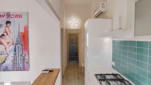 A modern kitchen with a gas stove, a wooden countertop, and a poster of a woman on a skyscraper. - Holiday apartment mit Klimaanlage und Balkon (San Michele al Tagliamento)