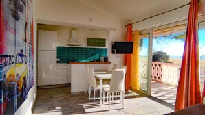 A compact kitchen with white cabinets, a green backsplash, and a flat-screen TV mounted above the counter. - Holiday apartment mit Klimaanlage und Balkon (San Michele al Tagliamento)