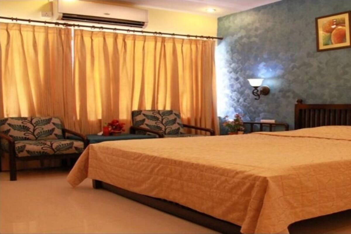 Una habitación de hotel con una cama grande, dos sillas, una mesita y una mesita de noche.
