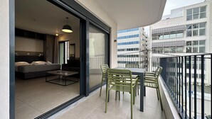 A balcony with a dining table and chairs, a sofa, and a bed in the adjacent room. - M & M 4 in the city - Jacuzzi Rooftop (XP92+FQ Athens, Greece)