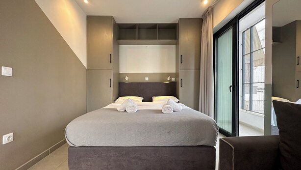 A modern bedroom with a large bed, built-in wardrobe, and a balcony with a view. - M & M 4 in the city - Jacuzzi Rooftop (XP92+FQ Athens, Greece)
