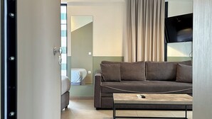A modern living room with a sofa, a coffee table, and a TV mounted on the wall. - M & M 4 in the city - Jacuzzi Rooftop (XP92+FQ Athens, Greece)