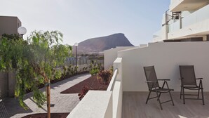 A modern outdoor seating area with two chairs, a landscaped garden, and a view of a mountain. - Ocean Paradise 1 La Tejita (Intero appartamento, due camere e un bagno) (Granadilla de Abona)