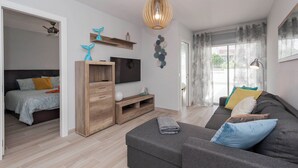 A modern living room with a sofa, a TV, a wooden cabinet, and a ceiling light. - Ocean Paradise 1 La Tejita (Intero appartamento, due camere e un bagno) (Granadilla de Abona)