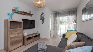 A modern living room with a grey sofa, wooden TV stand, and decorative wall art. - Ocean Paradise 1 La Tejita (Intero appartamento, due camere e un bagno) (Granadilla de Abona)