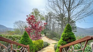 A stone pathway leading to a mountain view, flanked by wooden railings and surrounded by lush greenery and trees. - 4 Mi to Sapphire Ski! Mtn-View Cabin w/ Deck (Sapphire)
