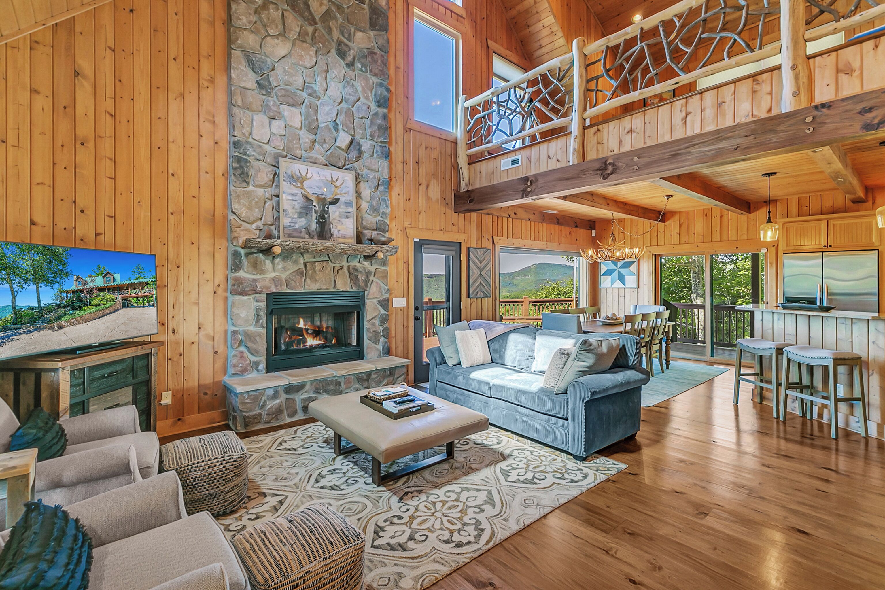 A spacious living room with a stone fireplace, a blue sofa, and a wooden ceiling.