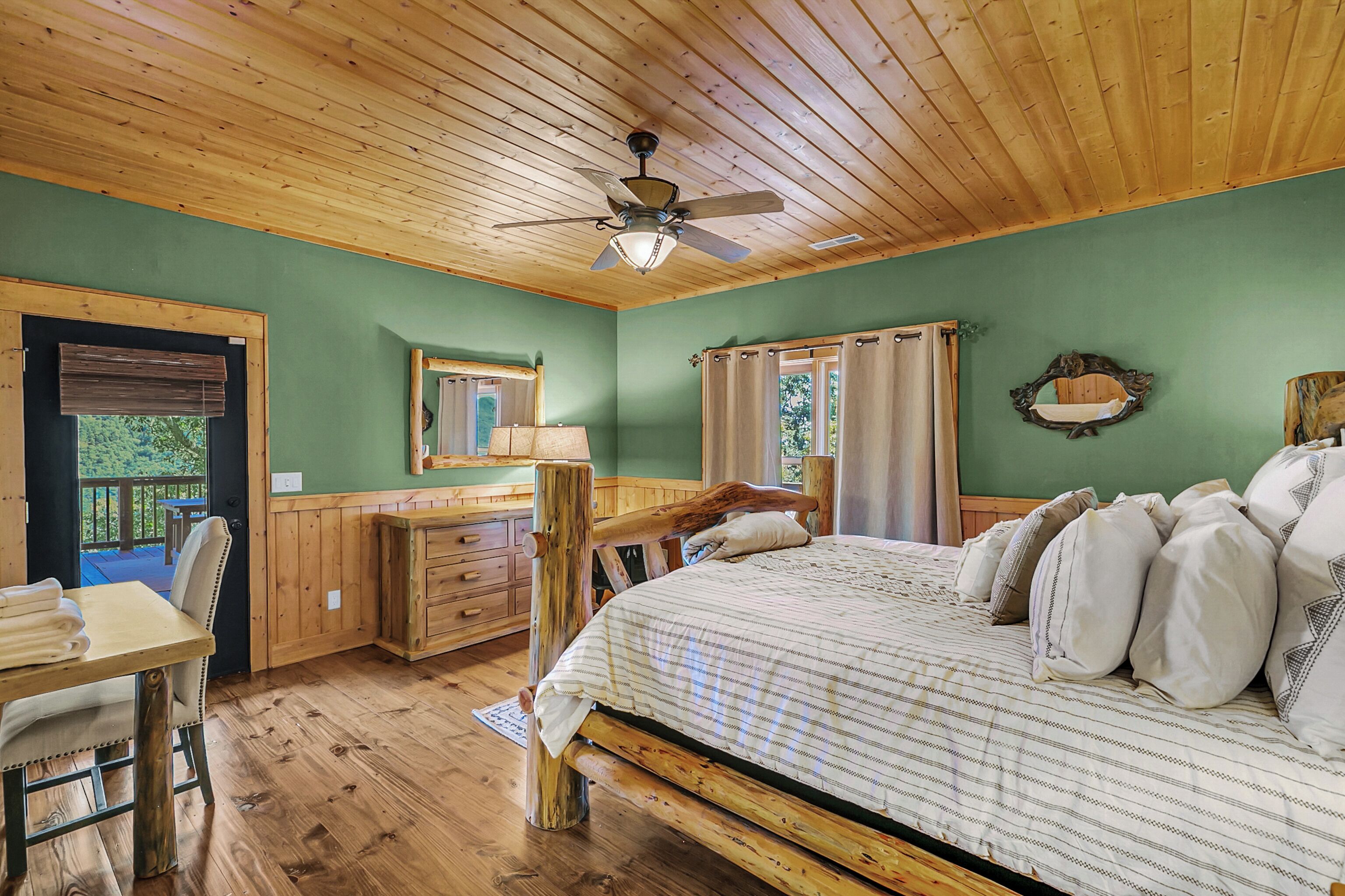 A wooden bedroom with a bed, a desk, and a chair.