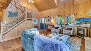 A wooden interior with a staircase, a sofa, a chair, a table, and a painting. - 4 Mi to Sapphire Ski! Mtn-View Cabin w/ Deck (Sapphire)