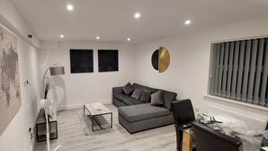 A modern living room with a grey sofa, a small coffee table, a floor lamp, and a map on the wall.