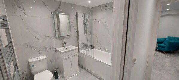 Un bagno moderno con una parete in marmo, un lavabo, un water e una vasca da bagno.