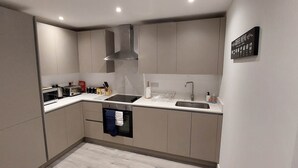 A modern kitchen with a built-in oven, stainless steel sink, and a range hood.