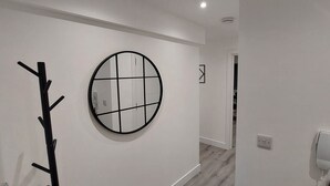 A hallway with a coat rack, a round mirror, and a telephone on the wall.