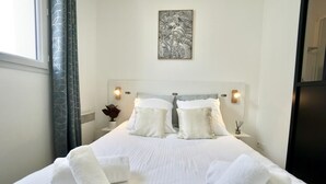 A hotel room with a large bed, two bedside lamps, a wall-mounted artwork, and a window with curtains.