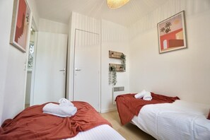 A hotel room with two beds, a door, a wall-mounted plant, and a framed picture. - Swing *swimming pool * golf* (Quéven)